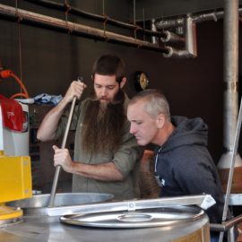 A brewer instructs a man in brewing